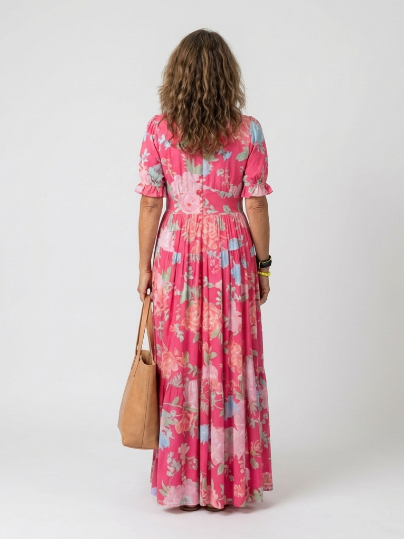 Rear view of a woman wearing a pink floral short-sleeve midi dress, holding a tan leather tote bag.