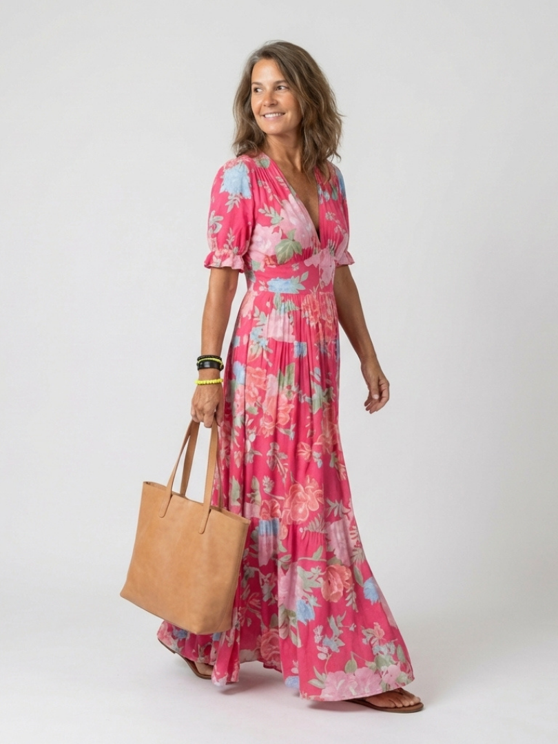 Model wearing a pink floral midi dress with short sleeves, V-neck, and tiered skirt, holding a tan tote bag.