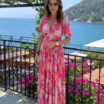 Pink V-neck midi dress with short sleeves and a blue and pink floral print.