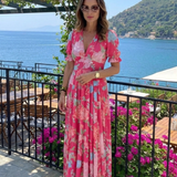 Pink V-neck midi dress with short sleeves and a blue and pink floral print.